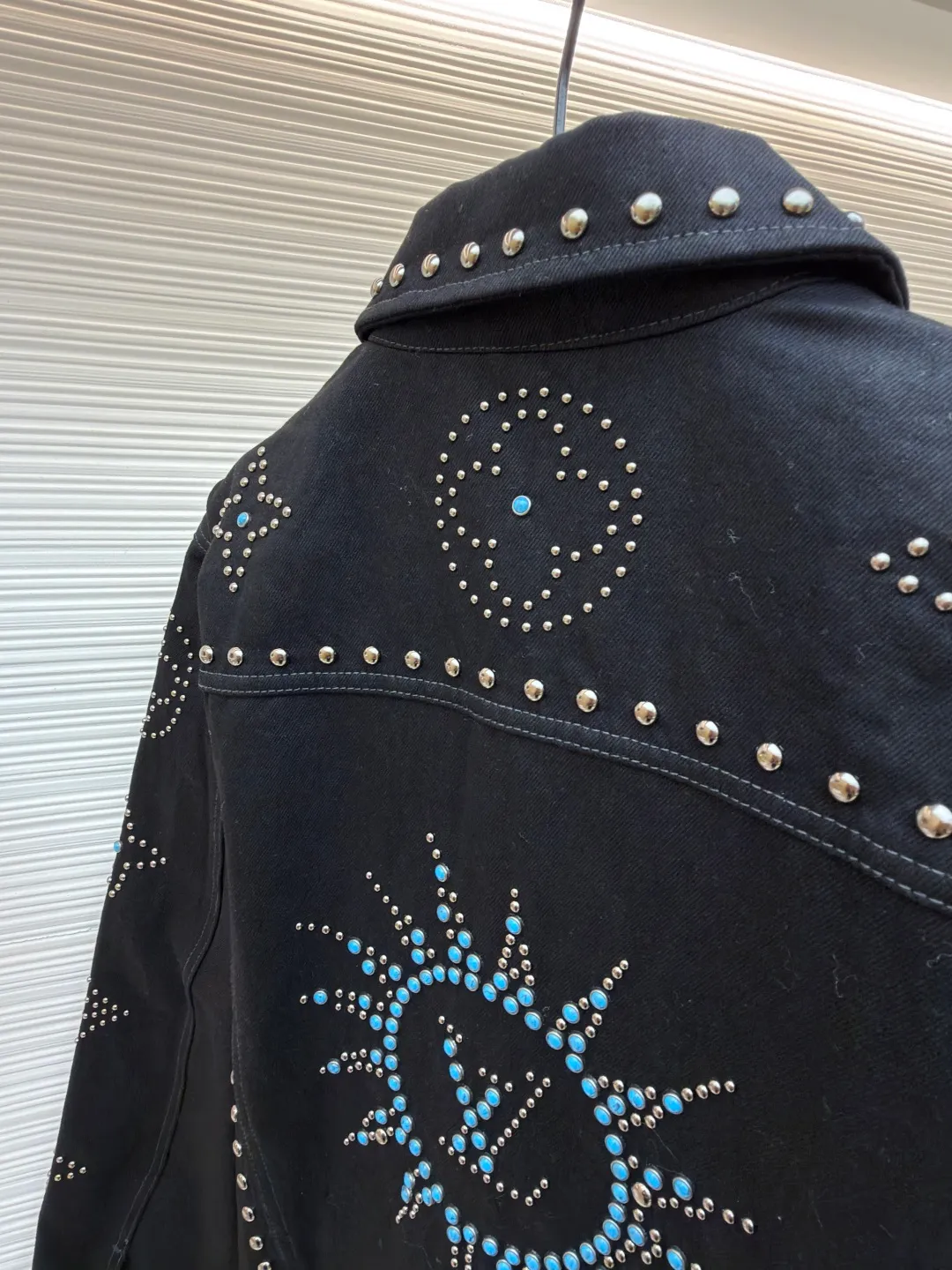 LOUIS VUITTON turquoise rivet denim jacket ●Original version: purchased and developed by 38979 ●Item number: 1682224-E30 ●Material: denim fabric ●Technology: hand-made rivet inlay ●Color: black ●Version: fitted version ●Weight: about 1550 grams ●Size: 46-48-50-52 ●Description: This black denim jacket is made of high-density twill denim fabric and has been treated with pre-washing water. It not only retains the crisp texture of the fabric, but also achieves a soft and skin-friendly wearing experience. The entire body of the garment is made of hand-made rivet inlay technology. The metal rivets are arranged at precise points to outline the outline of the brand's classic logo. Each rivet is manually hammered and fixed to ensure firmness and three-dimensionality. The placket and pockets are decorated with turquoise-textured resin buttons, which contrast with the metal rivets. The stitching on the collar, cuffs and hem adopts a double stitching process to enhance structural stability, while the edges are roughened to add a retro texture. The overall cut is a slightly loose Oversize version, combined with the three-dimensional tailoring process of the three-dimensional shoulder line, taking into account both styling and wearing comfort. Every detail is calibrated by hand, demonstrating the exquisite level of clothing making technology. The overall wiring is straight and delicate, the fabric is comfortable and soft, and the color is consistent without color difference. It can be matched with the same style to create a fashionable look and control various occasions. Customized accessories, complete with three standards, same style for men and women!